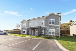A multi-story building with a parking lot and a grassy area in front. - Branson’s Like Home Hideaway (Branson)