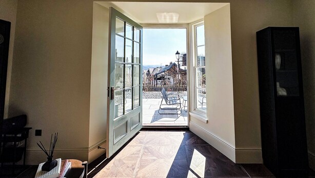 A hallway with a glass door leading to an outdoor terrace.