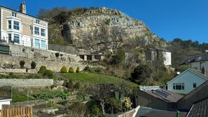 A residential area with a prominent cliff, stone walls, and houses with bay windows.