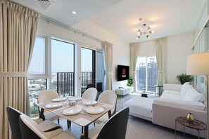 Relax in a spacious living room with a panoramic city view, dining area, and comfortable seating for socializing.