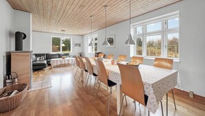 Un comedor amplio con una mesa larga, sillas e iluminación colgante.
