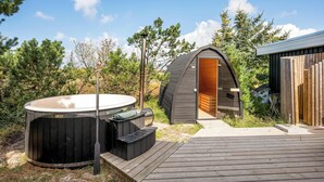 A hot tub, a sauna, and a wooden deck in a natural setting.