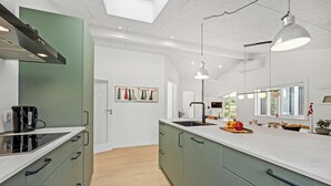 A modern kitchen with a large island, white countertops, and green cabinets.