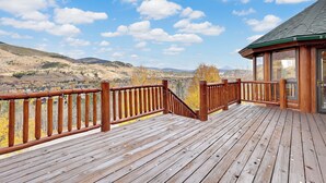 Une terrasse en bois dotée d’une balustrade, offrant une vue sur un paysage montagneux.