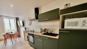 A modern kitchen with dark green cabinets, a built-in oven, a microwave, and a sink. - D-DAY SUITES carentanlocation.fr: TERRA - Downtown / 2-minute walk from the train station (Carentan-les-Marais)