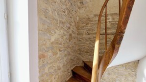 A spiral staircase with wooden steps and a stone wall. - D-DAY SUITES carentanlocation.fr: TERRA - Downtown / 2-minute walk from the train station (Carentan-les-Marais)