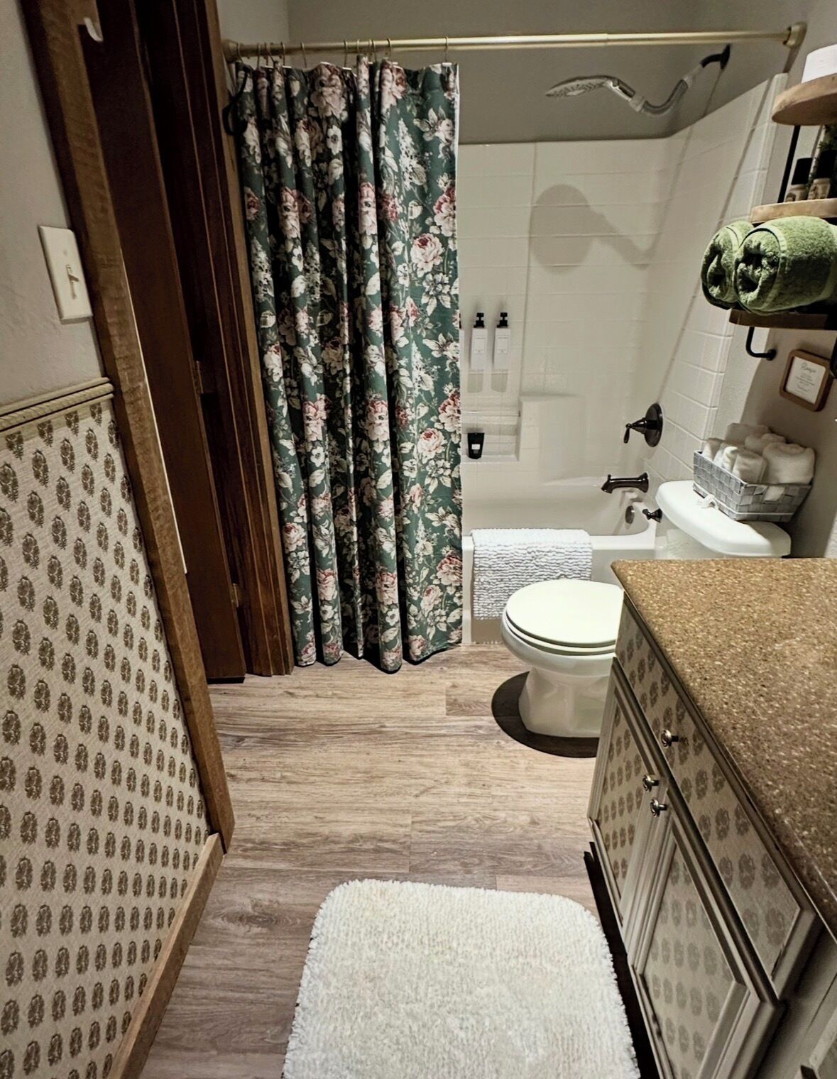 A bathroom with a toilet, shower, and sink.