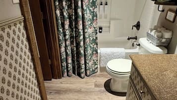 A bathroom with a toilet, shower, and sink.