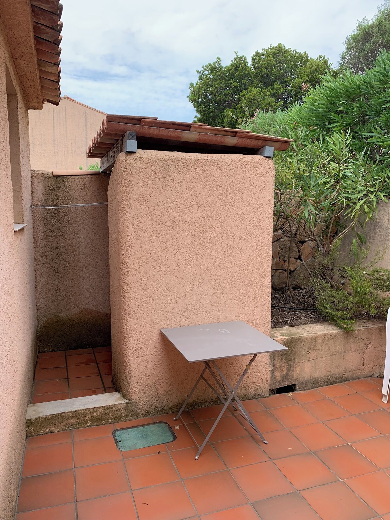 Een terras met een metalen tafel en een stenen muur.
