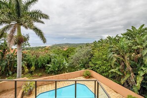 A pool surrounded by lush greenery and a view of the ocean. - San Lameer Villa 13924 (Southbroom)
