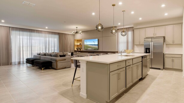 Una cocina moderna con una isla central, electrodomésticos de acero inoxidable y una zona de comedor con sofá y sillas.