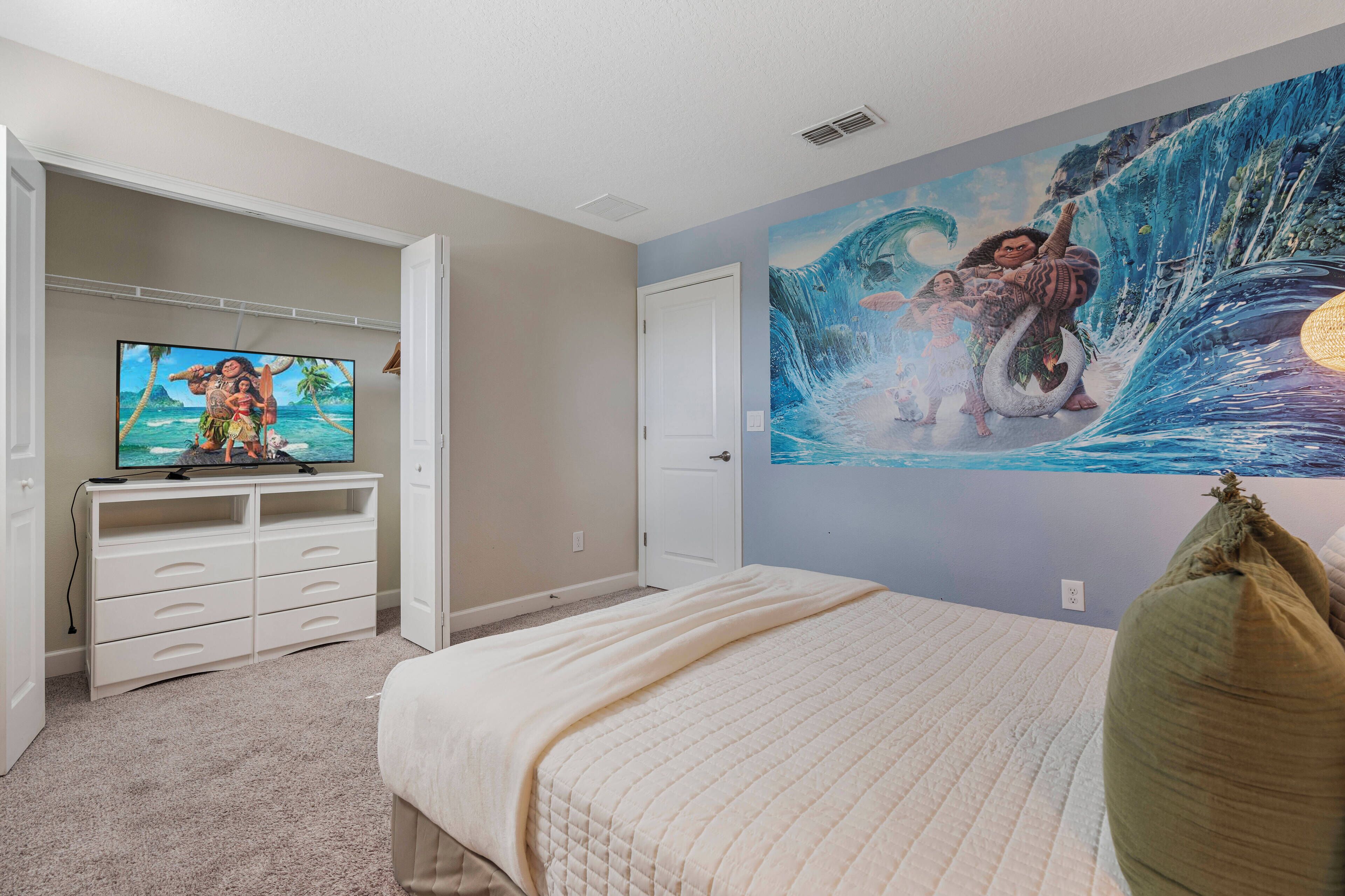 Una camera da letto con un letto, una TV, una cassettiera e un affresco al muro.