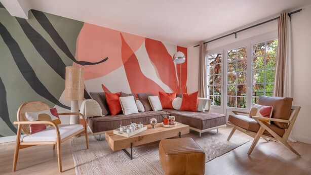 A modern living room with a sofa, chairs, a coffee table, and a large abstract painting on the wall.