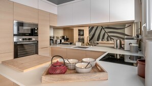 A modern kitchen with built-in appliances, a wooden countertop, and a decorative leaf pattern on the backsplash.