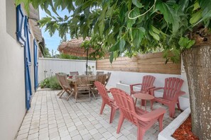A patio with a table and chairs, a wooden fence, and a tree providing shade. - 200m from the beach, nice house for 6 (Préfailles)
