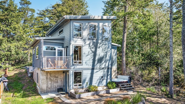 A multi-level cabin with a balcony, surrounded by trees.
