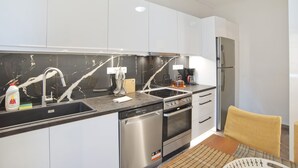 A modern kitchen with white cabinets, a black marble backsplash, stainless steel appliances, and a ceiling fan. - Afrodite Classic Residence, 2BR, WiFi, City View (Paleo Faliro)