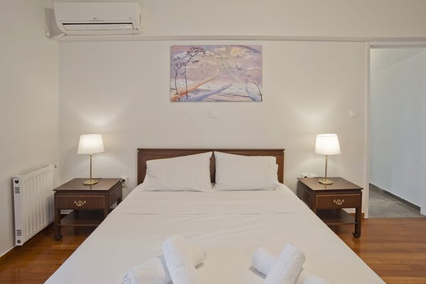 Ein Hotelzimmer mit einem großen Bett, zwei Nachttischen mit Lampen, einem Heizkörper und einem Bild an der Wand.