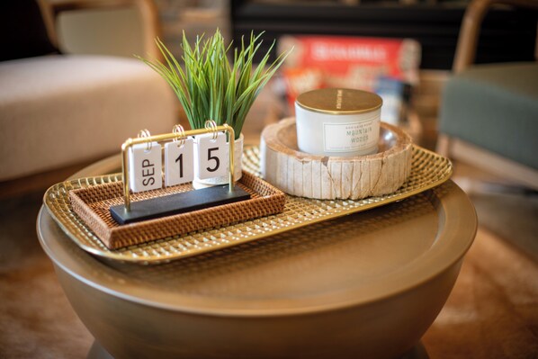 A decorative tray with a date display, a small plant, and a container on a ceramic table.
