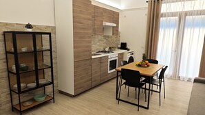 Eine moderne Küche mit Essbereich, ausgestattet mit einem Holzschrank, einem Einbauofen und einem Esstisch mit Stühlen.