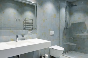 A modern bathroom with a large mirror, a white sink, a toilet, and a glass-enclosed shower area. - Roze Peldu Residence (Liepaja)