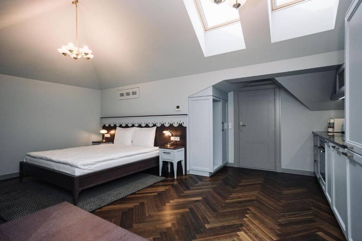 Une chambre dotée d’un grand lit, de tables de chevet, d’un bureau et d’une kitchenette.
