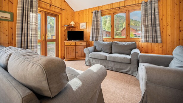 A cozy living room with a sofa set, a television, and a wooden cabinet.