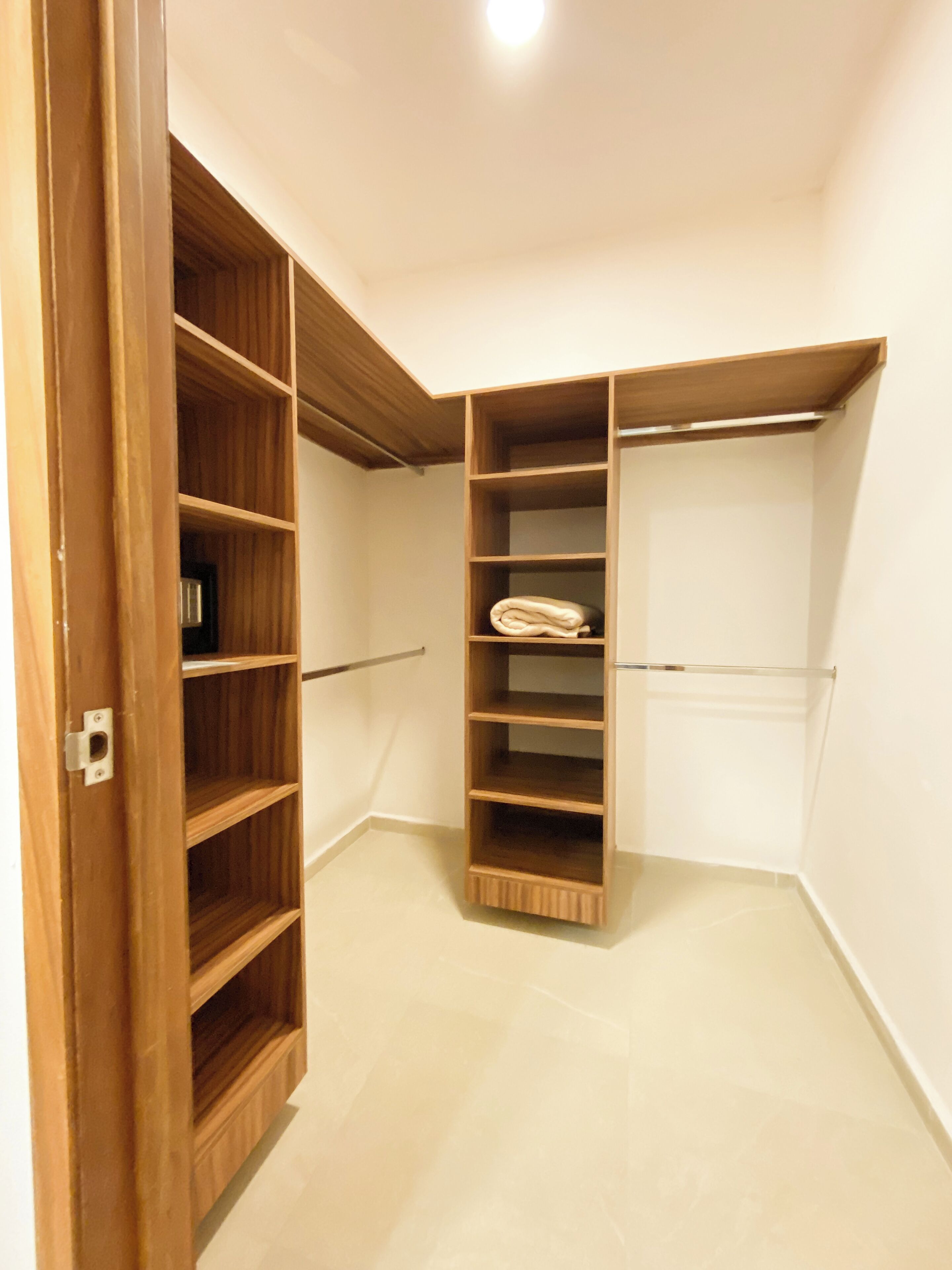 Un vestidor con estantes de madera y una barra metálica para colgar ropa.