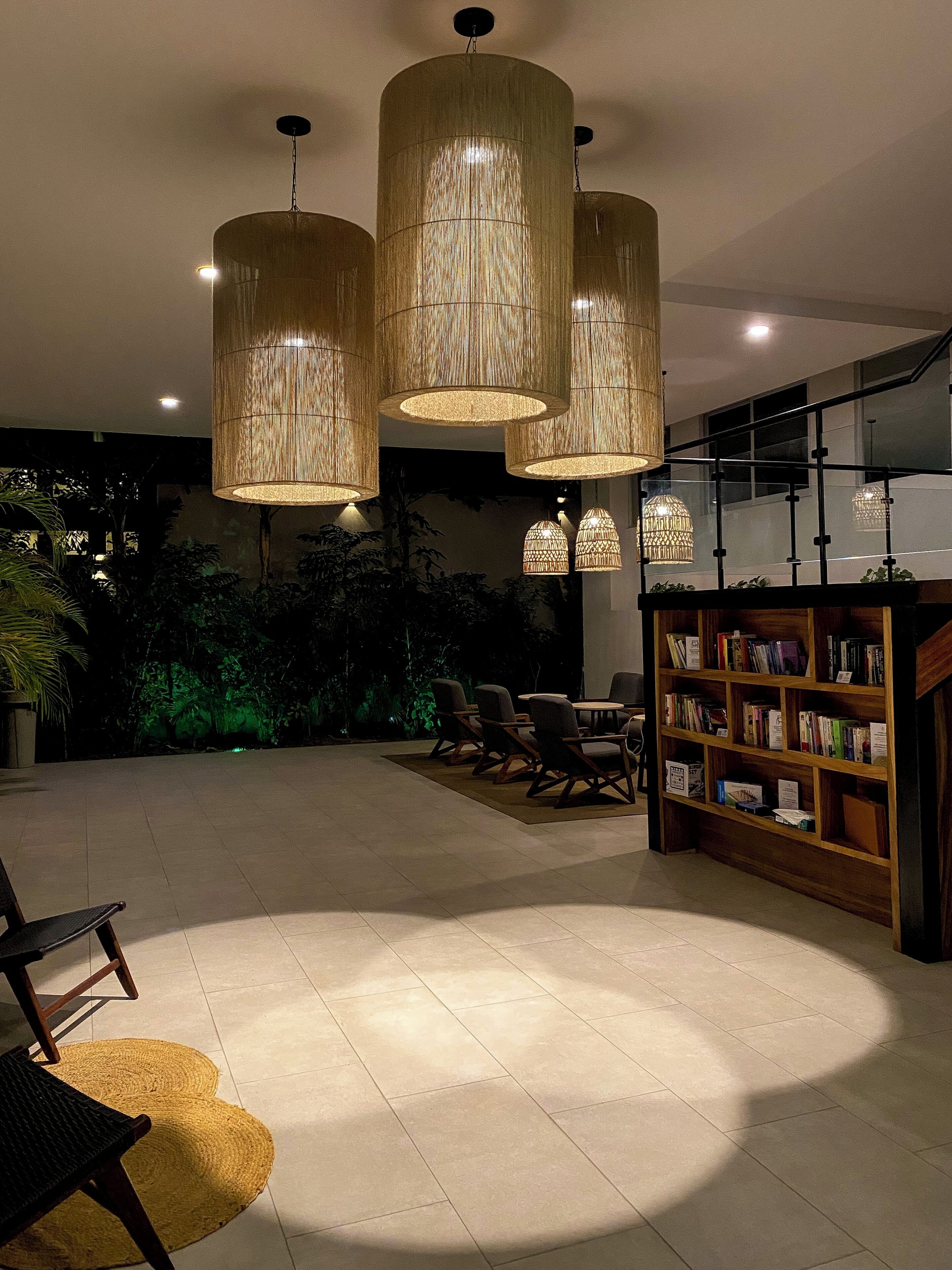 Un'ampia area interna con una grande libreria, diverse poltrone e lampade a sospensione.