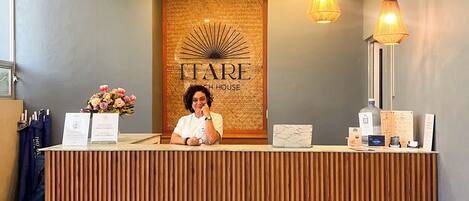 A reception desk with a wooden finish, a wall with a sunburst design, and two hanging pendant lights.