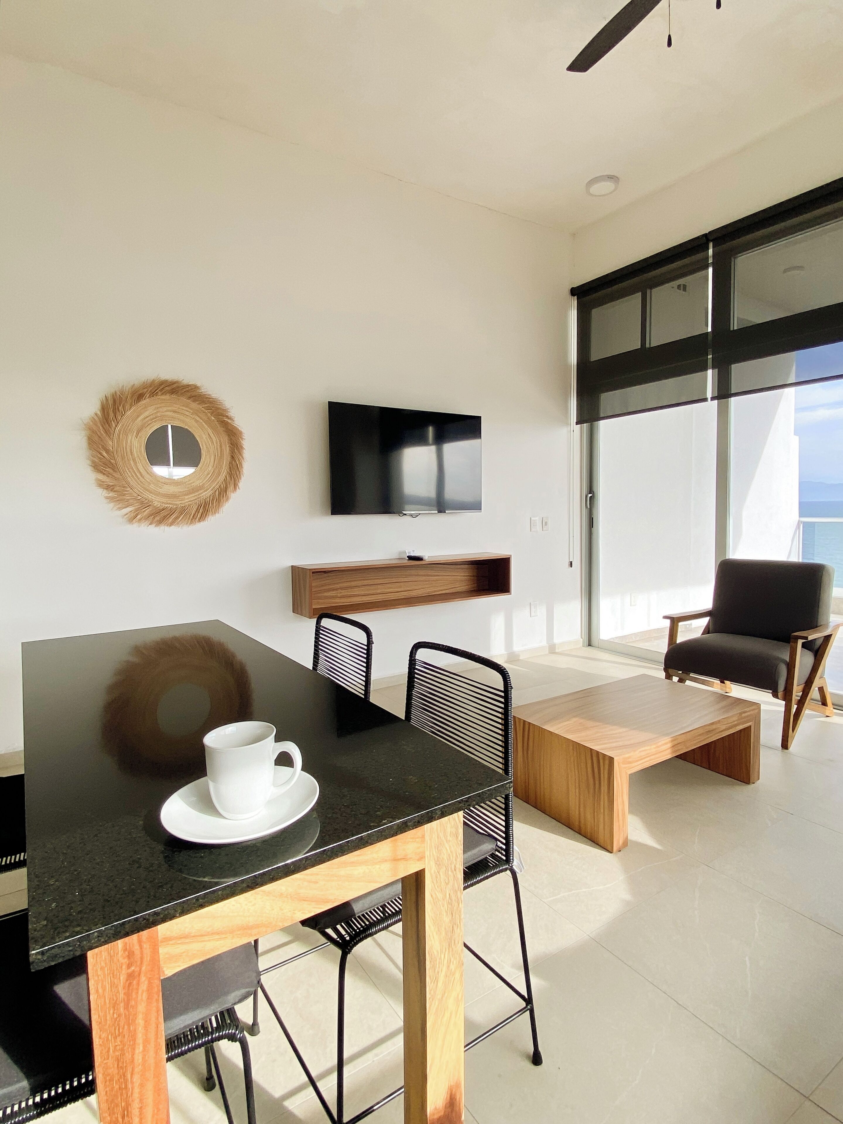 Un comedor moderno con una mesa negra, una taza blanca y decoración tejida en la pared.
