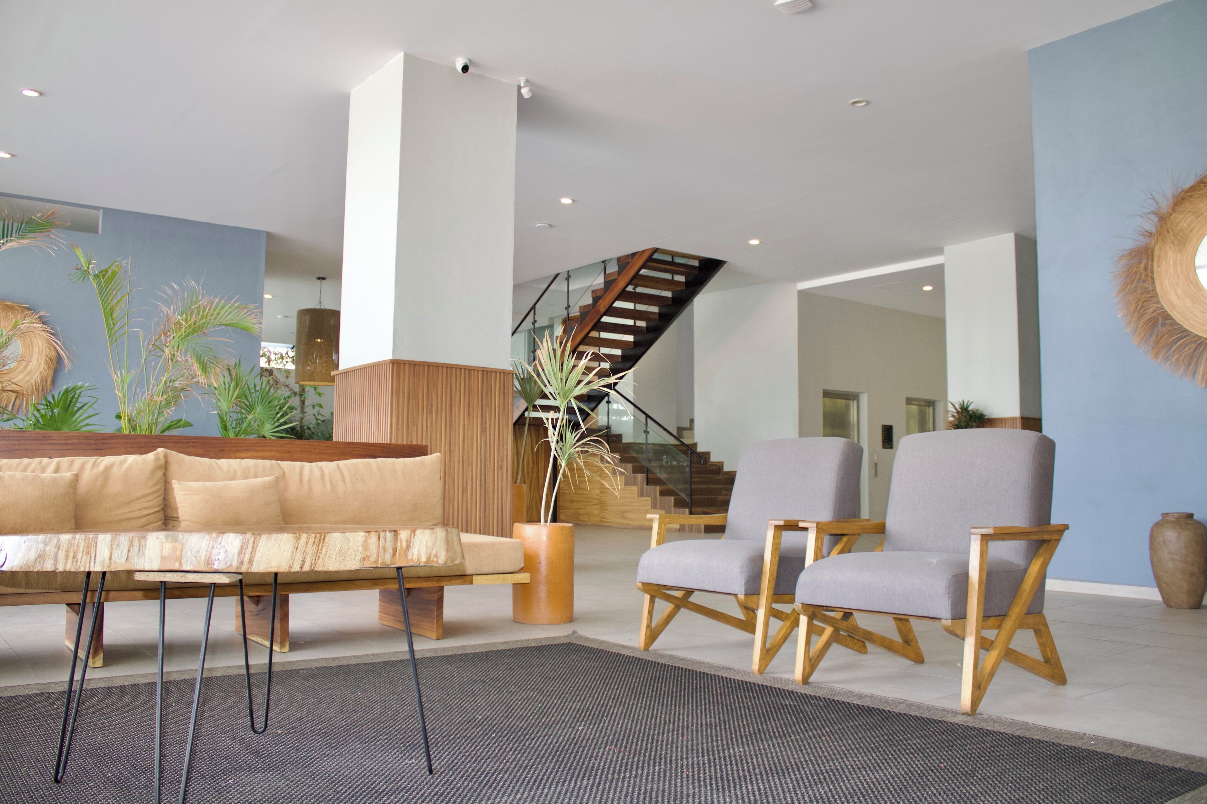 A modern interior with a sofa, two armchairs, a coffee table, and a staircase.