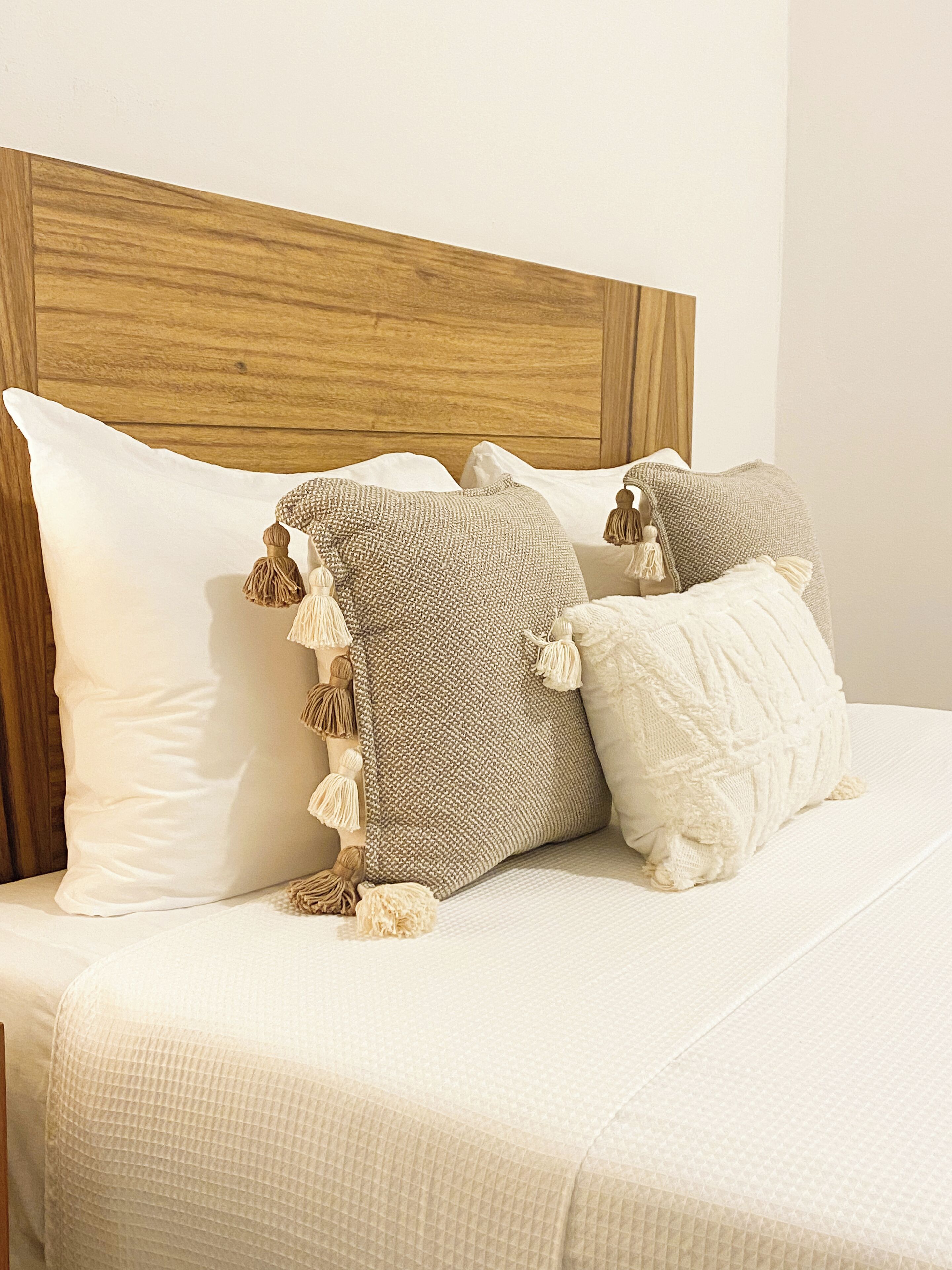 A bed with a wooden headboard, white pillows, and textured blankets.