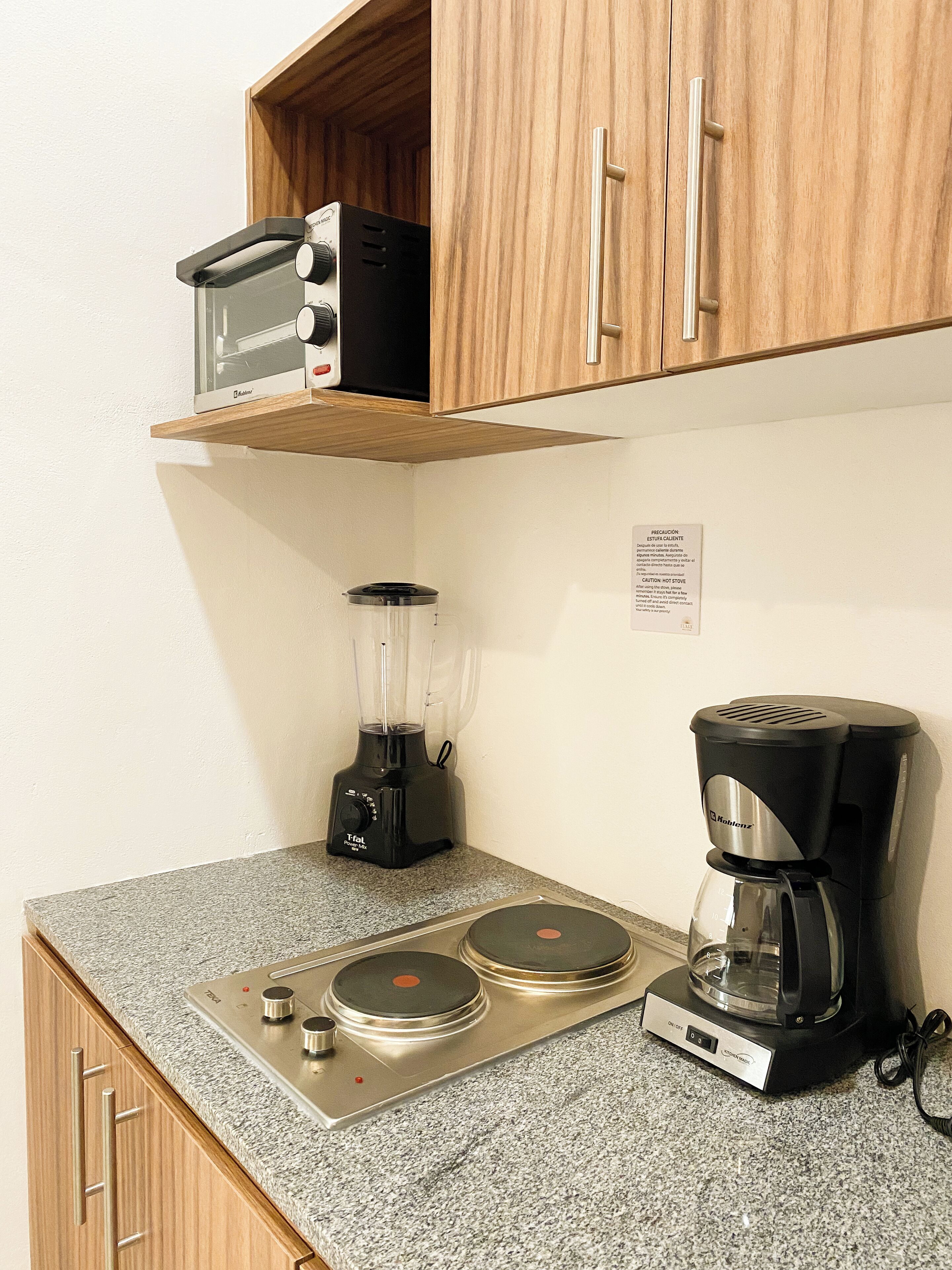 Una kitchenette con cafetera, licuadora y tostadora sobre una encimera de granito.