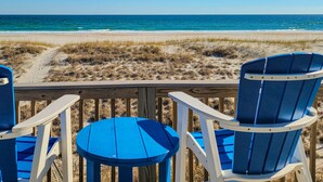 A beach view with two blue Adirondack chairs and a small round table on a wooden deck. - Albion: Dive Into Oceanfront Bliss! (Topsail Beach)