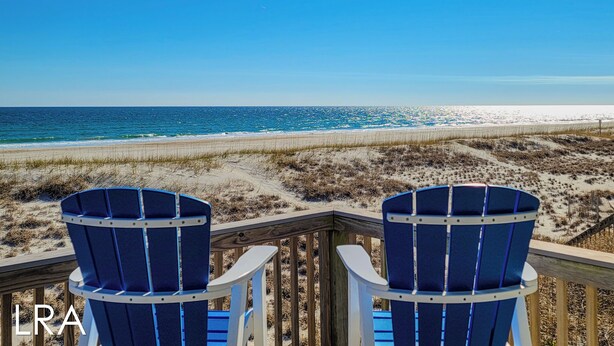 Two blue Adirondack chairs on a wooden deck overlooking a beach with a clear view of the ocean. - Albion: Dive Into Oceanfront Bliss! (Topsail Beach)
