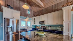 A modern kitchen with white cabinets, stainless steel appliances, and a central island. - Albion: Dive Into Oceanfront Bliss! (Topsail Beach)