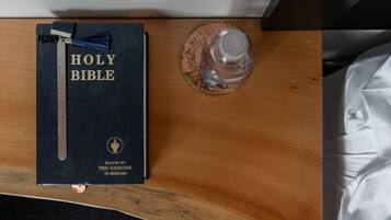 Una Biblia sobre una superficie de madera, con un separador metálico y un vaso de agua.