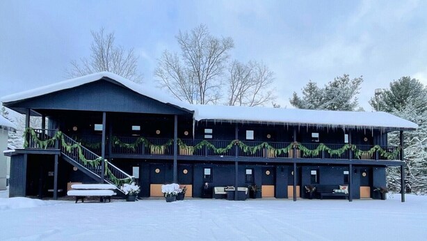 A two-story building with a covered porch and a staircase leading to the upper level. - Lincoln Boutique Motel- Lower Room #6 (Ellicottville)