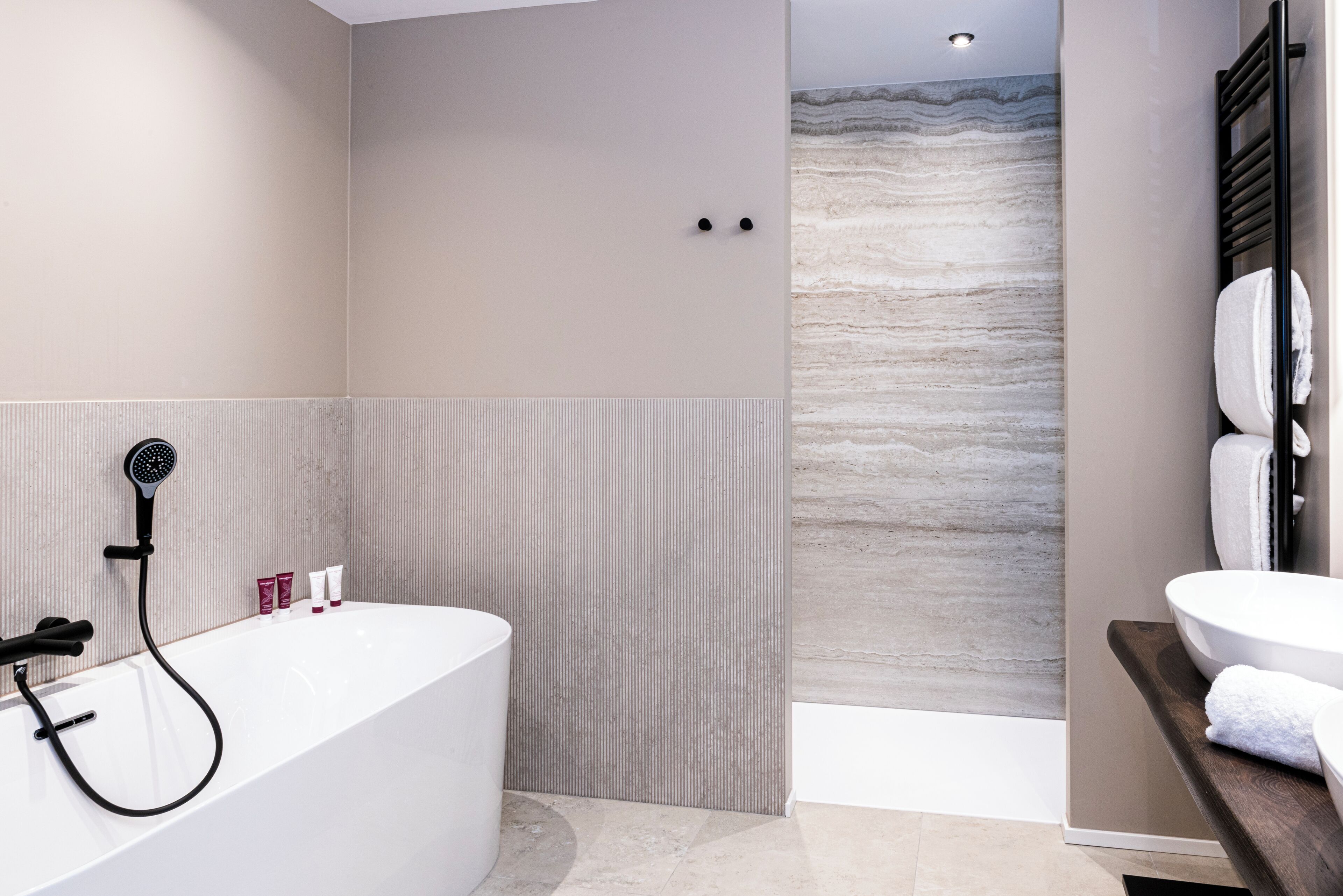 Un bagno moderno con una vasca da bagno freestanding, una doccetta e un porta asciugamani.