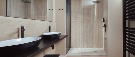 Une salle de bain moderne avec deux lavabos, une douche et un grand miroir.