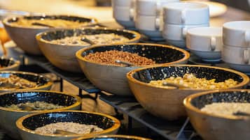 Un bufé con diversos alimentos servidos en cuencos y vasos.