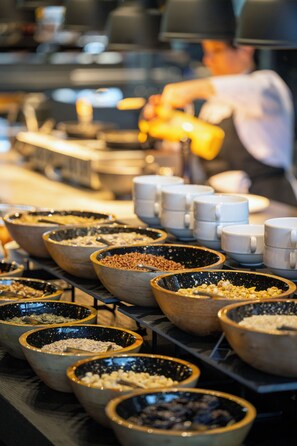 A buffet with various food items in bowls and cups.