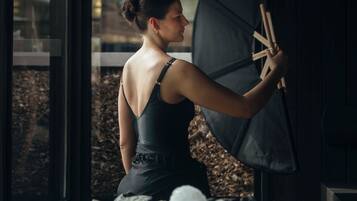 A person in a room with a large window, holding an umbrella.