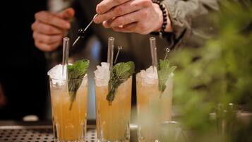 A bartender preparing drinks with straws and mint leaves.