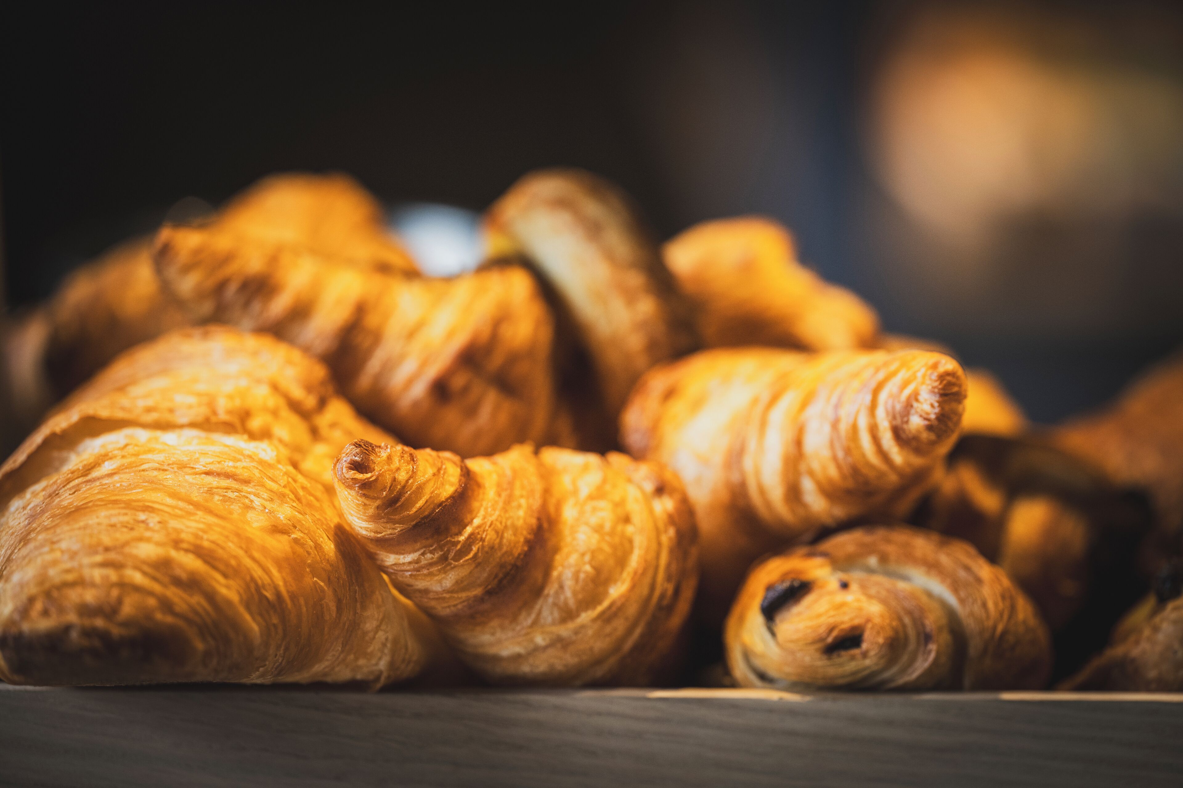 A close-up of a wooden surface with several golden-brown pastries, likely croissants, arranged on it.