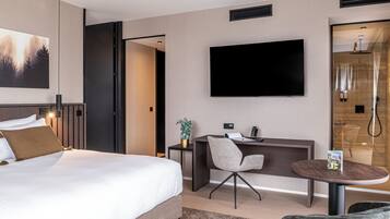 A modern hotel room with a large bed, a desk, a chair, a TV, and a small table.