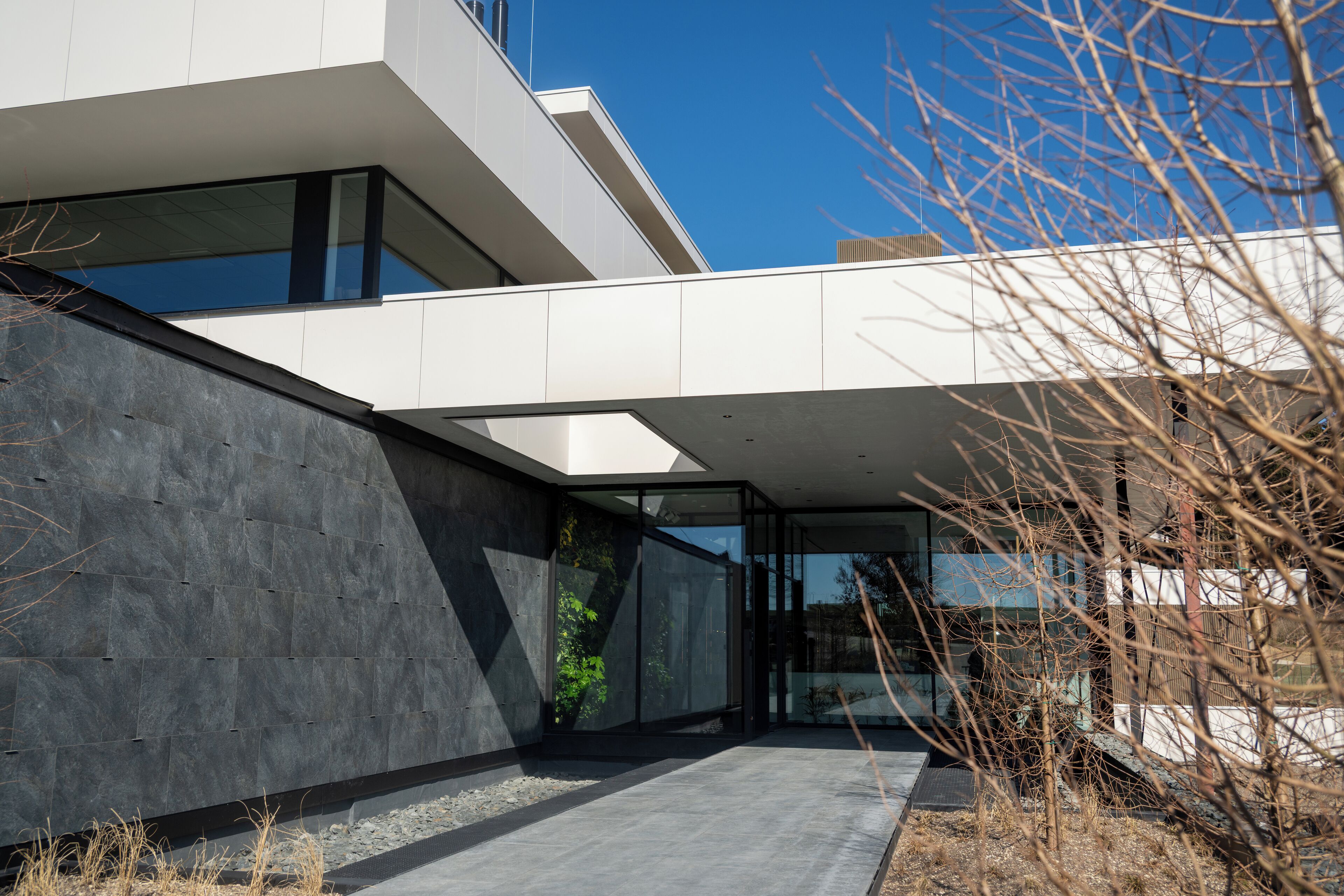 Een modern gebouw met een plat dak, grote ramen en een betonnen gevel.
