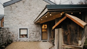 A stone building with a wooden porch and a window. - La Tanière - Nature and relaxation gîte (Durbuy)