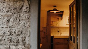 A narrow doorway leading into a kitchen with a stone wall on one side and wooden cabinets. - La Tanière - Nature and relaxation gîte (Durbuy)